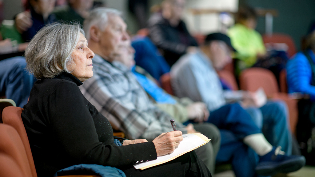 A woman holding a pen and taking notes